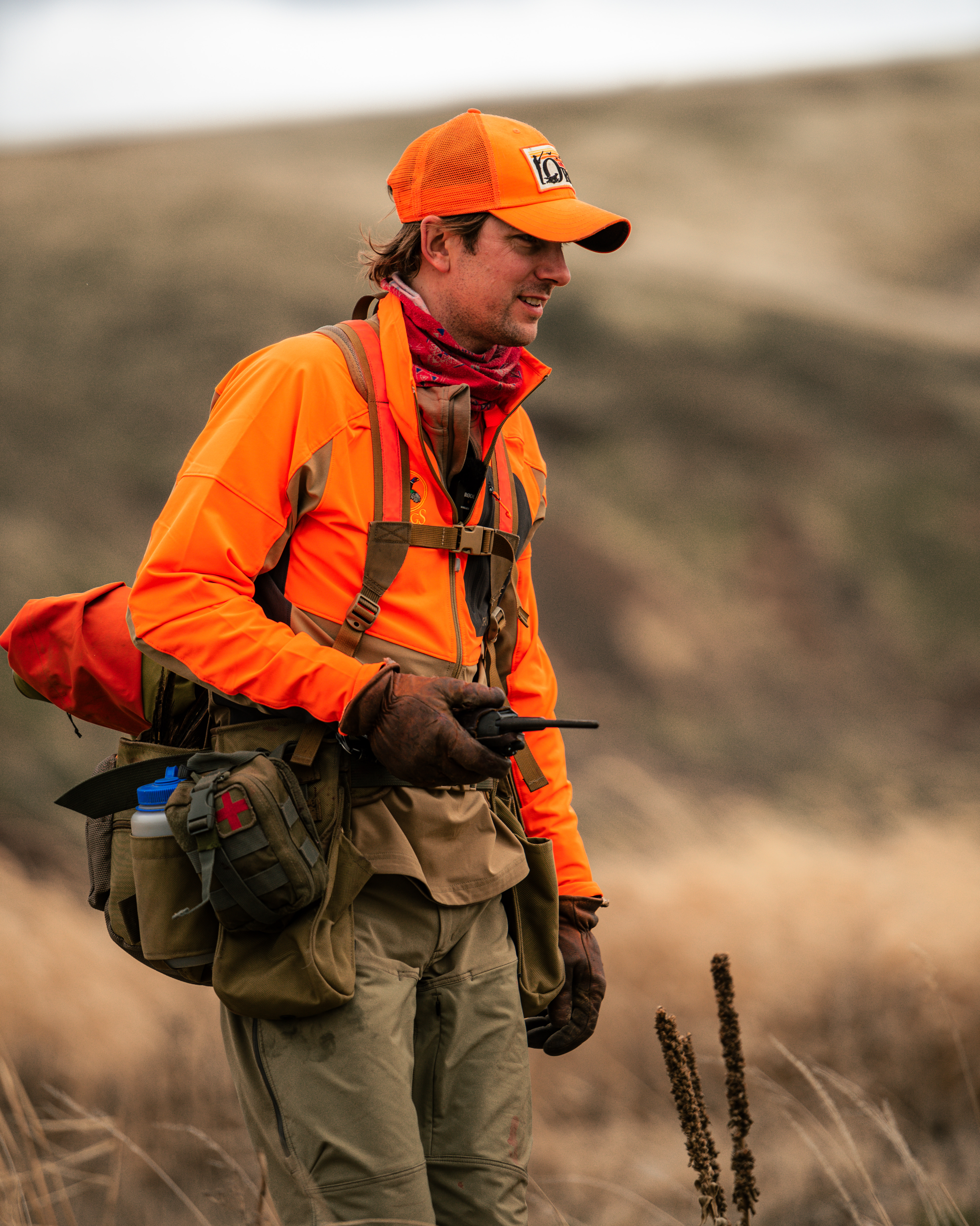 Hunter in blaze orange walking through tall grass